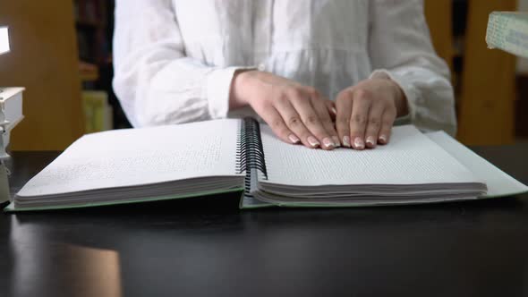 Blind Girl Reading a Text of Braille in Library alt