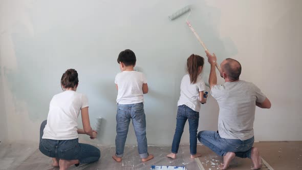 Caucasian Family Paints the Wall with a Roller Dad Mom Son and Daughter Together Make Repairs at
