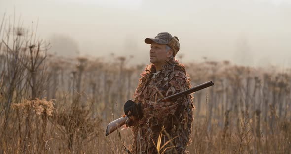 Portrait of Hunter with Shot Gun Standing in the Field and Looking Around, Foggy Autumn Morning alt