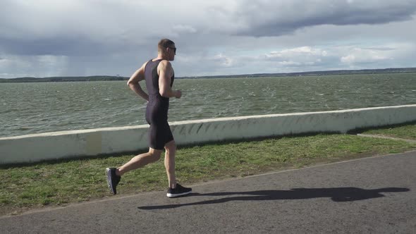 Prol Runner Runs on a Road Near the Lake Athlete Trains in on a Sunny Day Running Before Triathlon alt