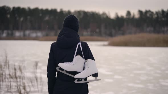 A Young Woman in a Dark Jacket, Came To the Frozen Lake To Go Ice Skating. In Winter, Nature Can Be alt