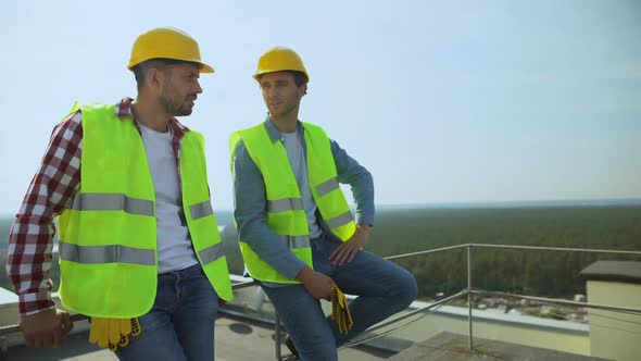 Two Construction Workers Talking During Work Break on Building Roof, Occupation