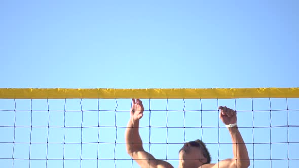 A man spiking a beach volleyball alt