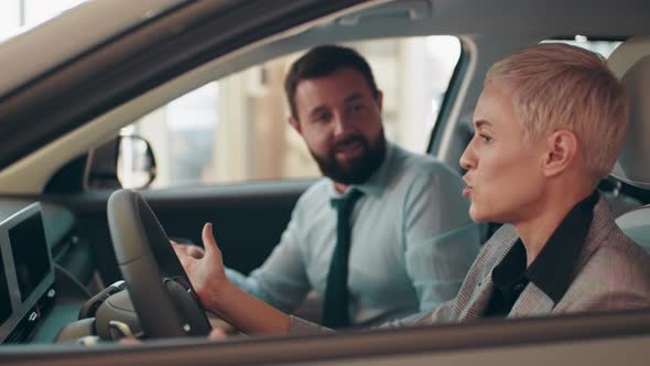 Blond Business Woman Sitting Inside Modern Auto Looking at Dashboards Design alt
