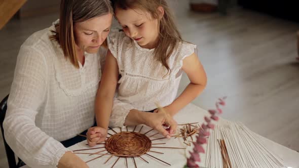Smiling Woman Teaching Paper Vine Basket to Daughter at Home