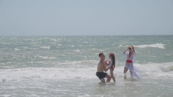 Man Tosses Daughter Standing in Endless Ocean Shallow Water