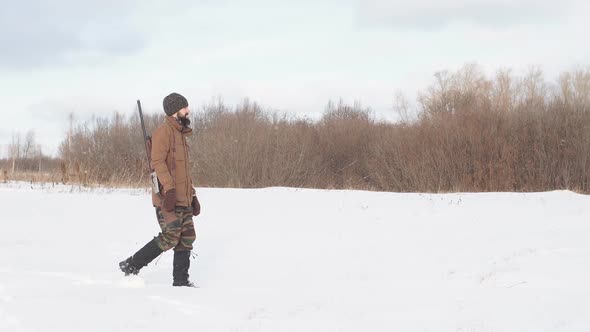 Male Warm Clothes Walking on the Field with Hunting Rifle. alt