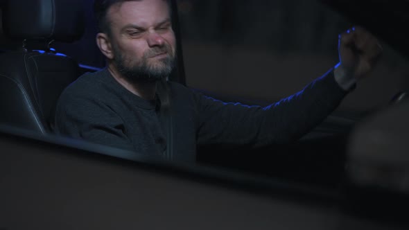 Man Sits in a Car Upset That He Was Stopped By the Police for a Traffic Violation alt