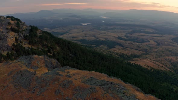 Hiker standing on ridge enjoying view to distance at sunset alt