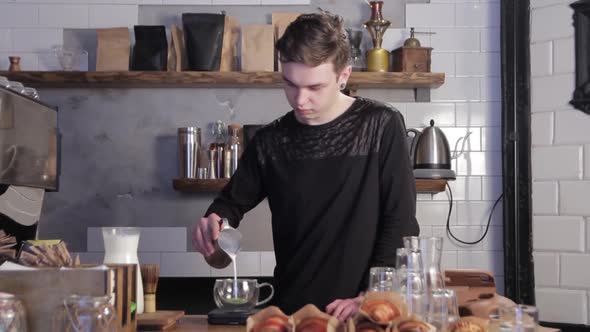 Man preparing Matcha green tea. Barista pouring milk into Matcha tea.