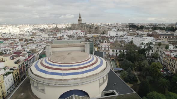 Teatro de la Maestranza with colored striped dome and cathedral in background, Seville in Spain.