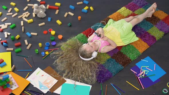Long-Haired Child Listening to Music in Earphones on Smartphone, Singing Song alt