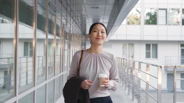 Asian Businesswoman Going to Work Drinking Coffee Outside Office Building alt