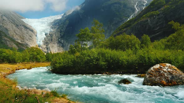 Clear Water in a Mountain Stream Against the Background of a Glacier in the Mountains alt