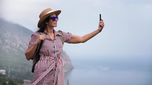 Elegant Female Smiling Posing on Top of High Mountain Over Sea Taking Selfie Use Smartphone alt