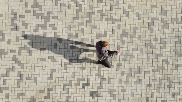 A Man Dances Breakdancing Against the Background of Street Tiles alt