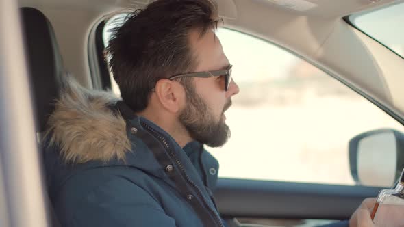 Drunken Driver Risk Car Accident. Man Holding Alcohol Bottle In Car. Dangerous On Road Drunk Driver. alt