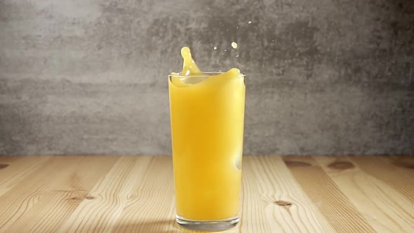 Ice Cube Fall into Glass with Orange Juice