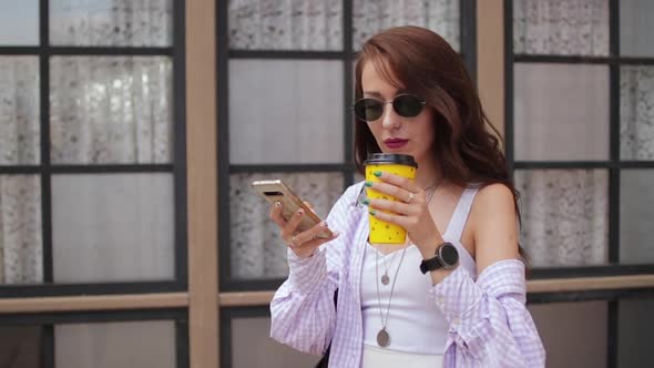 Beautiful Woman Holding A Coffee And A Smartphone On Street