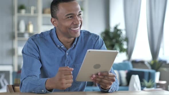 Young African Man Excited for Success while Using Tablet alt