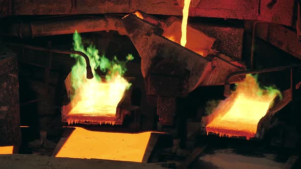 Smelter is Pouring Molten Copper Between Burning Molds alt