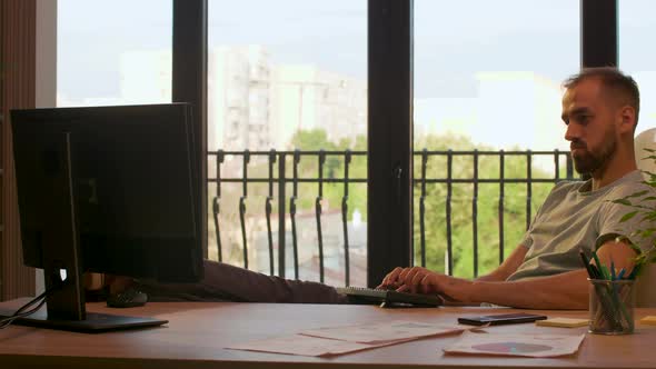 Businessman in Start-up Company Office Typing on PC with His Feet on the Desk alt