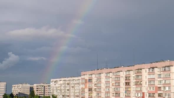 Huge Rainbow in the Cloudy Sky Above the Houses in City Timelapse alt