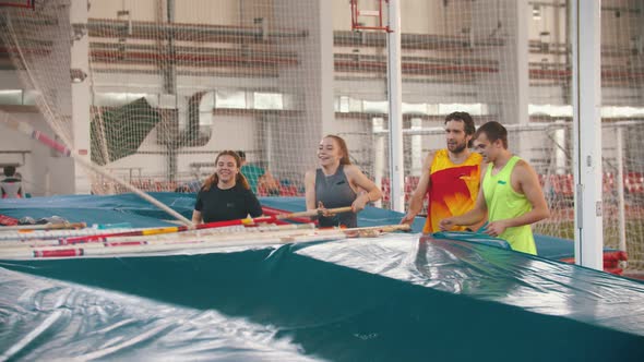 Group of Young People on the Pole Vault Training Taking Their Poles From the Mat alt