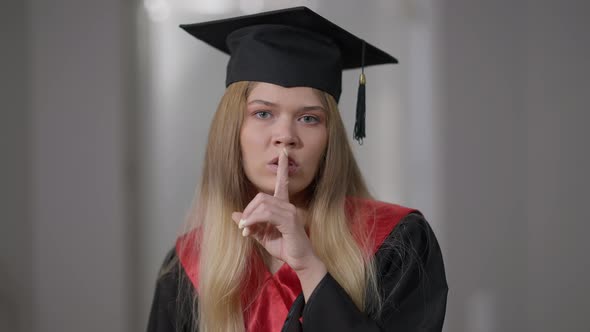 Portrait of Beautiful Caucasian Young Graduate Woman Gesturing Finger on Lips Hush Gesture Looking alt