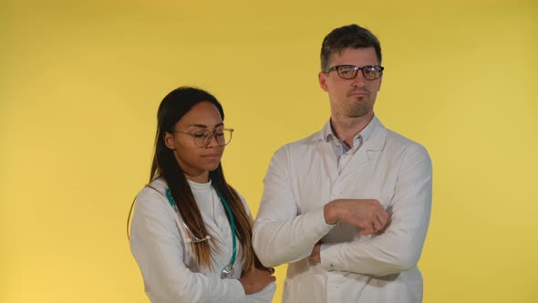 Diverse Doctors in Lab Coats and Eyeglasses Denying Something on Yellow Background. alt