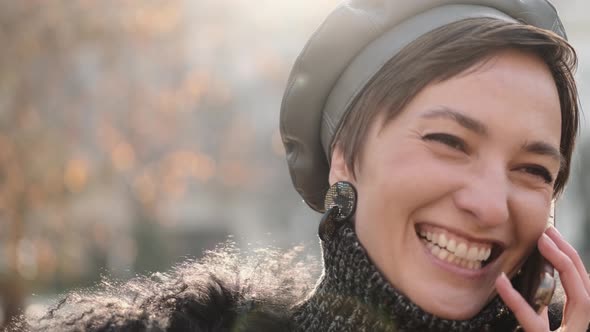 Close Up of a Gorgeous Happy Stylish Woman Smiling and Talking By Phone alt