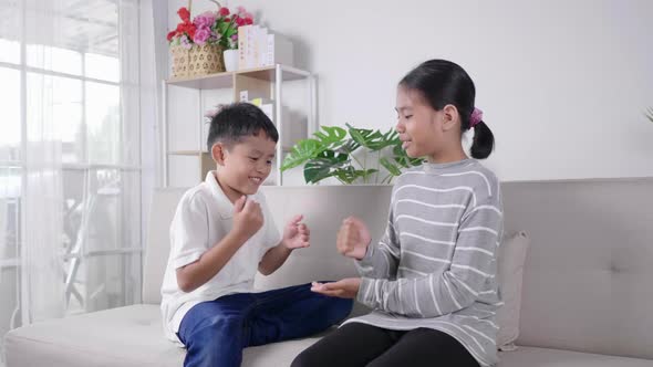 2 kids sitting and playing rock paper scissors game together with happy and laughing alt