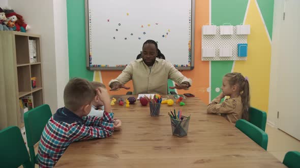 An African American Teacher and a Group of Children are Studying Fruits and Animals in the Classroom alt