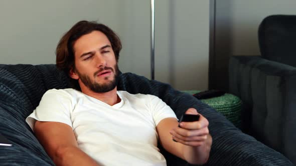 Man changing a channel and answering call in living room alt