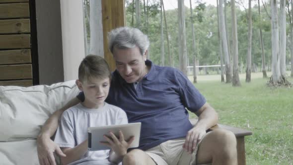Father and son looking at digital tablet together alt