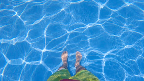 A slow motion shot of a person standing in a pool and enjoying the water and the summer