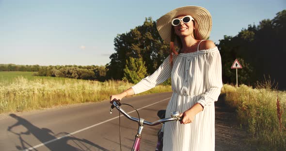 Woman Walking with Bicycle on Country Road