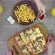Mother Putting Homemade Pizza on Table While Family Eating Fries - VideoHive Item for Sale