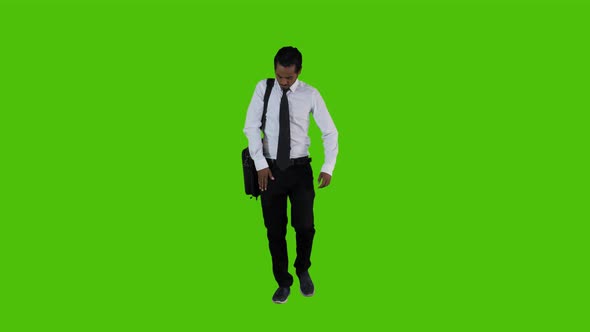  answering a Call While Walking by A Young Businessman Over a Green Screen alt