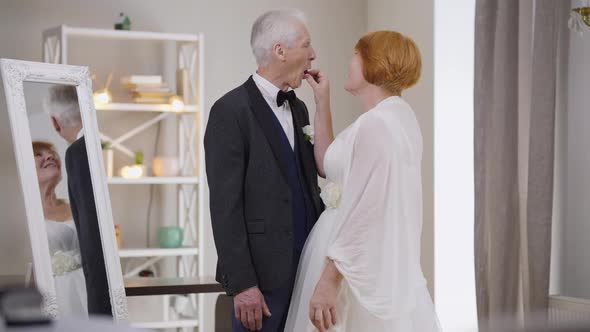 Loving Senior Bride Feeding Groom with Strawberry in Slow Motion Smiling alt