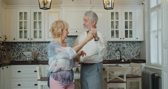 Elderly People Old Spouses Dancing in Kitchen Loving Husband Holds Hand of Beloved Wife While She alt