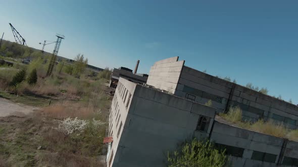 FPV Drone Flies Quickly and Maneuverable Among Abandoned Industrial Buildings and Near Excavators alt
