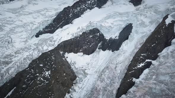 Aerial Approach to a alpin glacier in a mountain range on a cloudy day in Europe alt