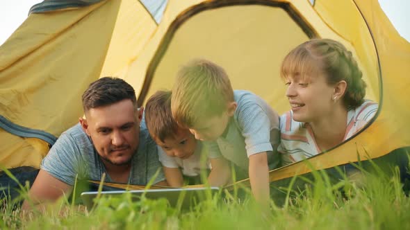 Parent and Child Playing Internet Computer Laptop Together in a Yellow Tent alt