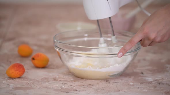 Beating butter with powdered sugar in a glass bowl using an electric mixer.	