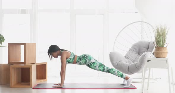 Black fit woman standing in plank position.