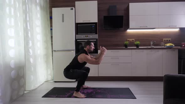 The Athlete Performs an Exercise on His Feet and Buttocks in the Home Kitchen alt