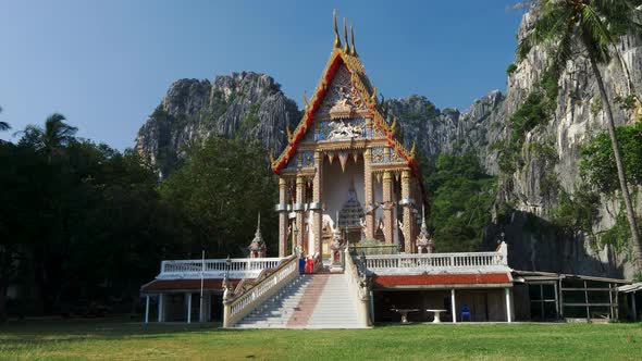 Ancient Traditional Buddhist Temple Wat Khao Daeng, Surrounded By Limestone Cliffs and a Rainforest alt