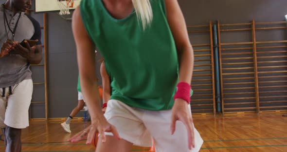 Diverse female basketball team and coach practice dribbling ball alt