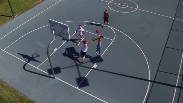Friends playing basketball at park, high angle shot